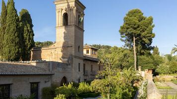 Un bâtiment historique doté d’un clocher, entouré d’une végétation luxuriante et d’arbres.