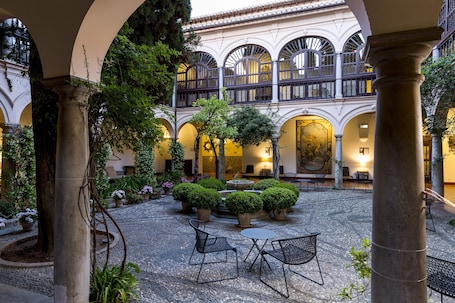A courtyard with a fountain, potted plants, and outdoor seating.