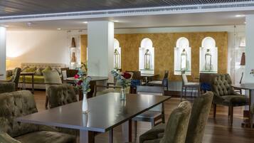 Un moderno vestíbulo de hotel con zona de comedor central, asientos cómodos y jarrones de cristal decorativos.