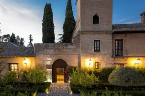 A historic building with a central arched entrance, brick walls, and a tiled roof. - Parador de Granada  (Granada)