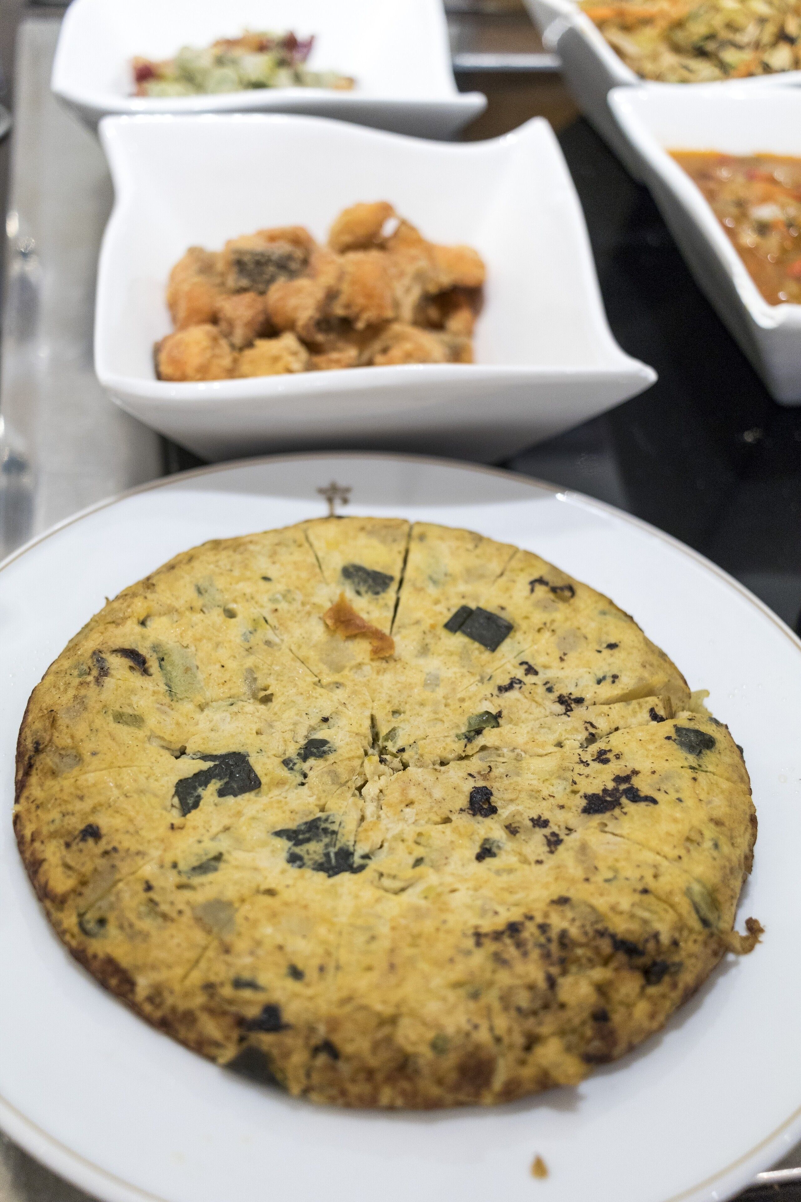 A round, baked dish with visible herbs on a white plate.