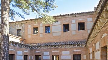 A courtyard with a stone building featuring a tiled roof, columns, and a bench.