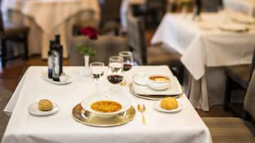 Een gedekte eettafel met borden, kommen, glazen en bestek, wat doet denken aan een restaurant.