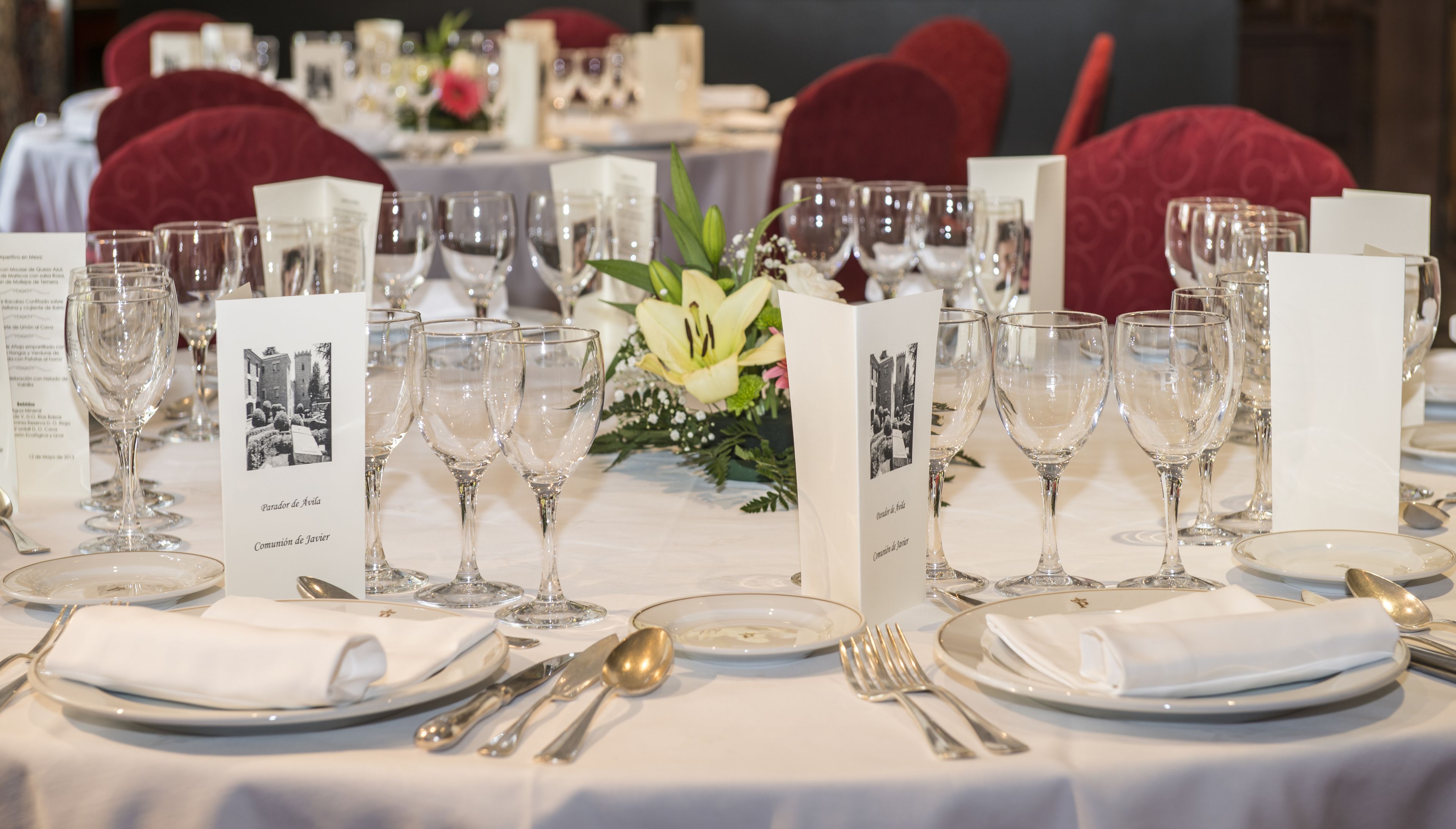 A table set for a formal meal with multiple wine glasses, plates, and cutlery.