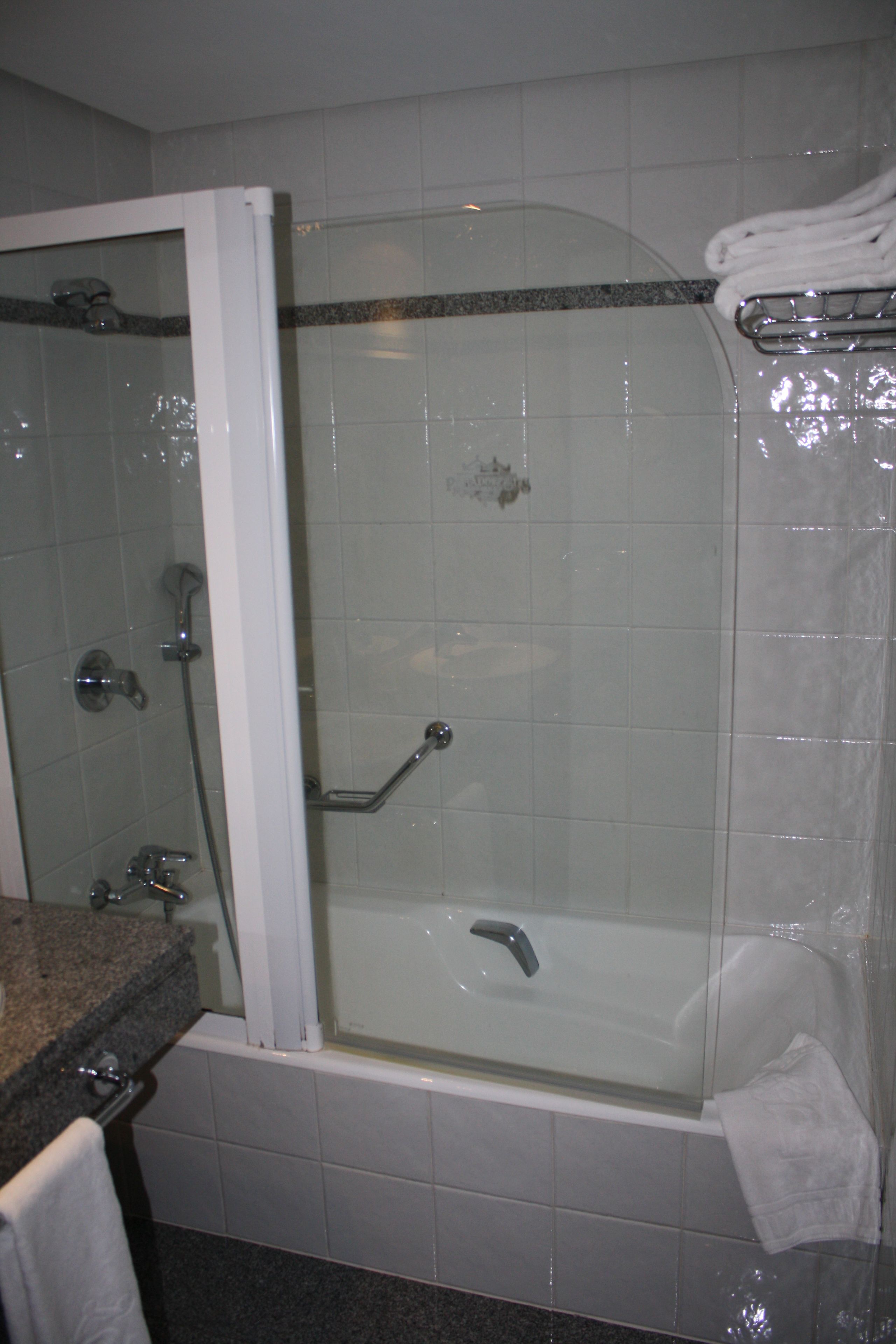 Un baño con ducha de vidrio, bañera y encimera de granito.