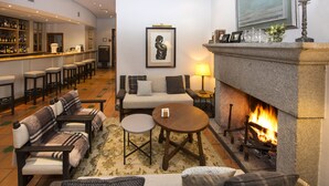 Un rincón de sala cómodo con chimenea, sofás, una mesa de centro y una barra con taburetes.