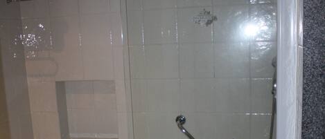 A bathroom with a bathtub, a shower enclosure, and a small stool.