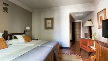 Habitación de hotel con dos camas, un sofá, un televisor y una mesita de noche con lámpara.