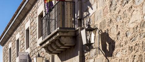 A stone building with a balcony, a flag, and a signboard.