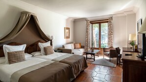 Habitación de hotel con dos camas, un escritorio, una silla y una ventana con cortinas.