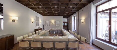 A conference room with a long table, chairs, and wall-mounted lights.