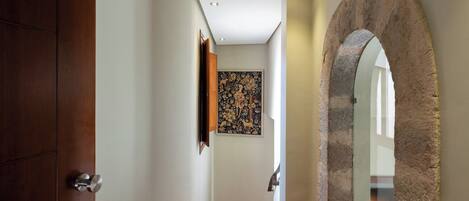 Un pasillo con una puerta de madera, un arco de piedra y una obra de arte enmarcada en la pared.
