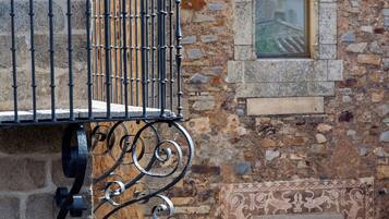 A stone building with a metal balcony and decorative ironwork.