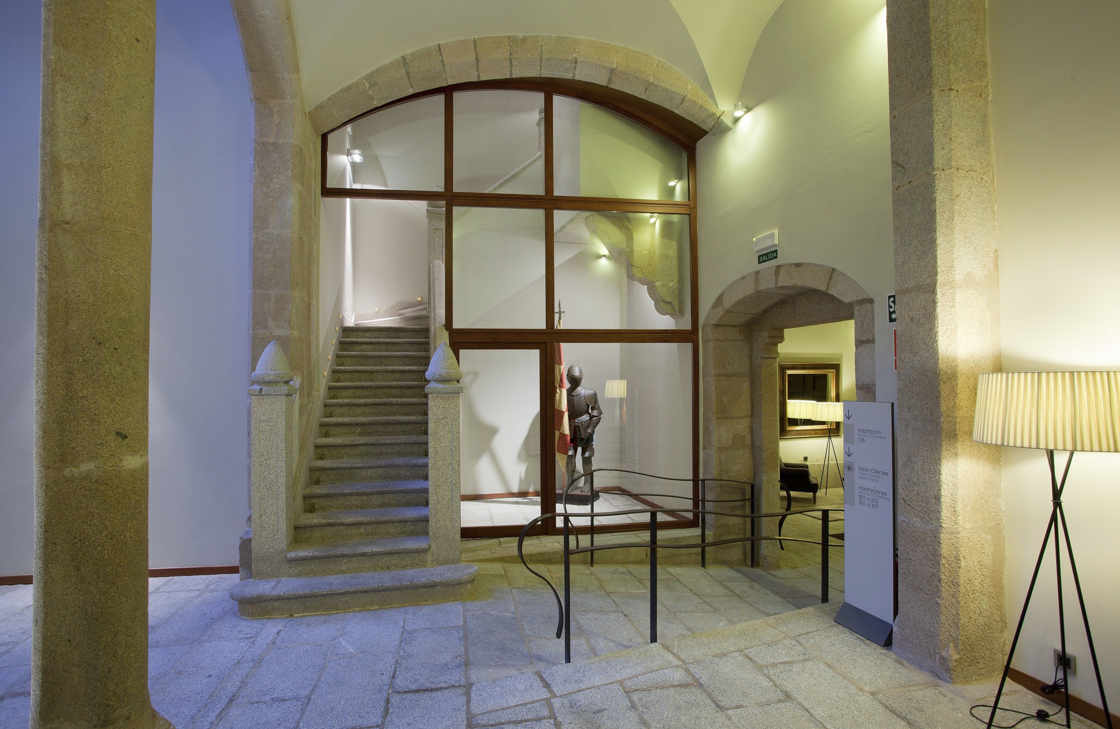 A stone staircase leading to a second floor, a glass partition, and a metal railing.