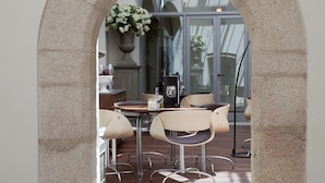 A stone archway leading to a dining area with a table and chairs, a potted plant, and a view through large windows.