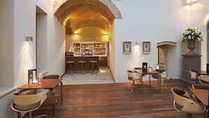 A cozy bar area with wooden flooring, a brick archway, and a bar counter with stools.