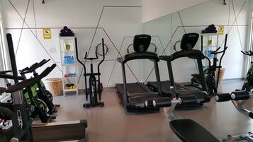 Una palestra con tapis roulant, cyclette e pesi liberi.