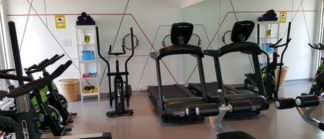 A gym with treadmills, stationary bikes, and free weights.