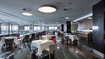 Un restaurante espacioso con techos altos, iluminación moderna y vistas a la ciudad.