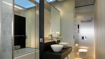 Une salle de bain moderne avec une douche à parois de verre, un grand miroir et un meuble-lavabo doté de deux vasques.