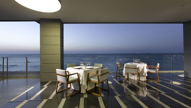 Un comedor con vista al mar, con una mesa para dos sillas.