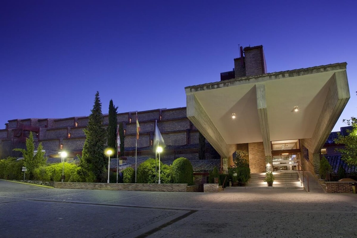 A modern building with a unique triangular roof structure, a brick facade, and a well-lit entrance.