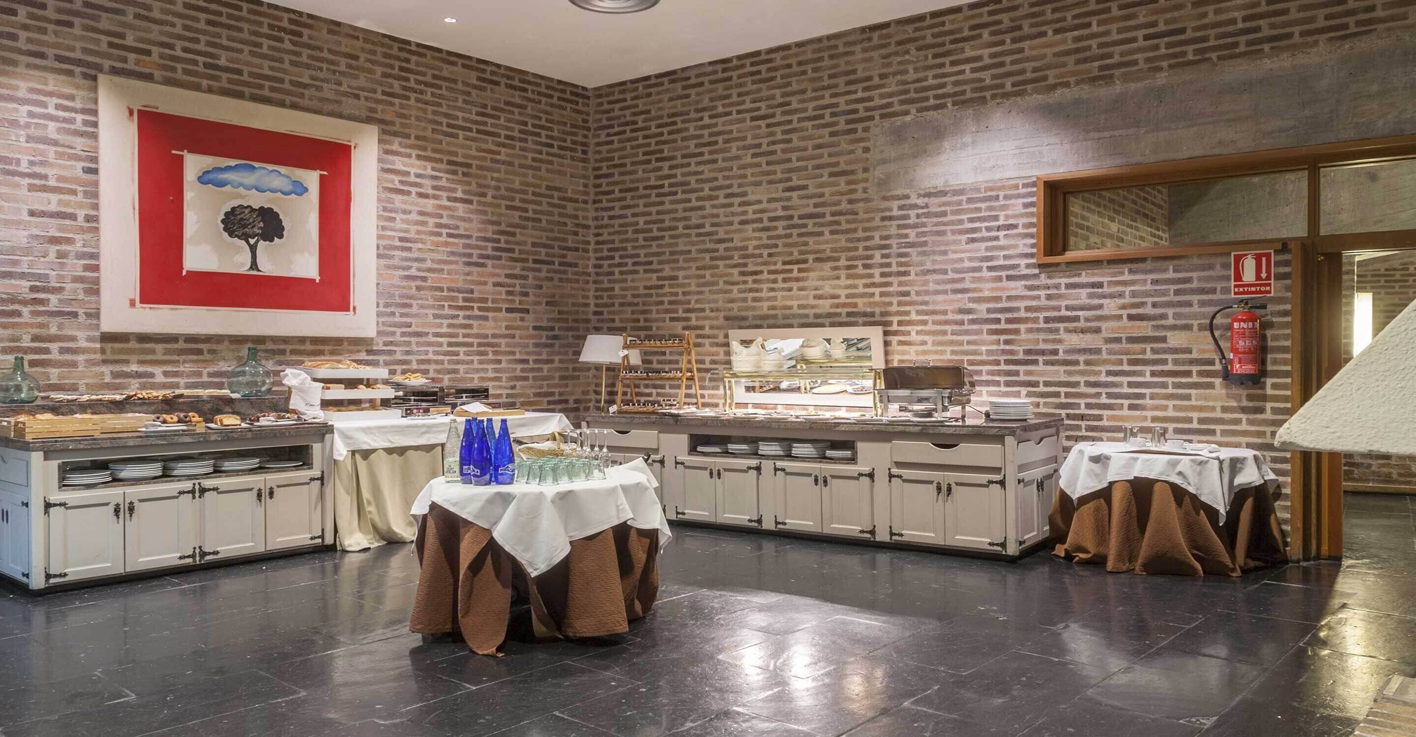 A restaurant with brick walls, a large painting, and multiple tables with food displays.