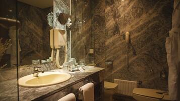 A bathroom with a marble sink, a mirror, a toilet, and a shower curtain.