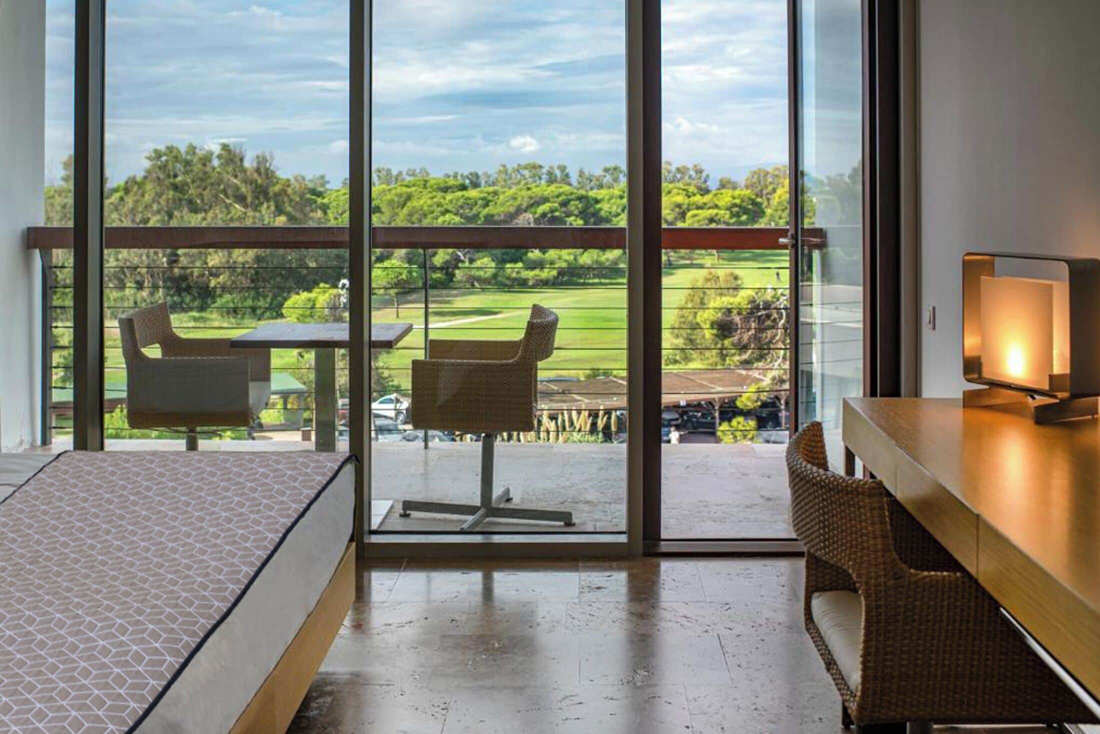 A modern room with a large sliding glass door leading to a balcony with a view of a golf course.