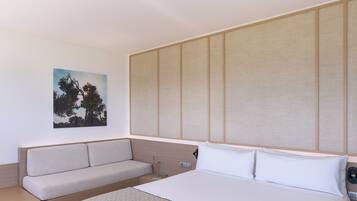 A modern hotel room with a bed, a sofa, and a large window.