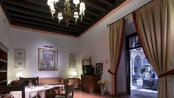 Comedor con candelabro, una mesa preparada para dos personas y vista a un patio exterior a través de una puerta.