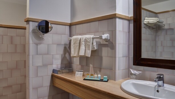 A bathroom with a sink, mirror, towel rack, and toiletries. - Parador de Úbeda (Úbeda)