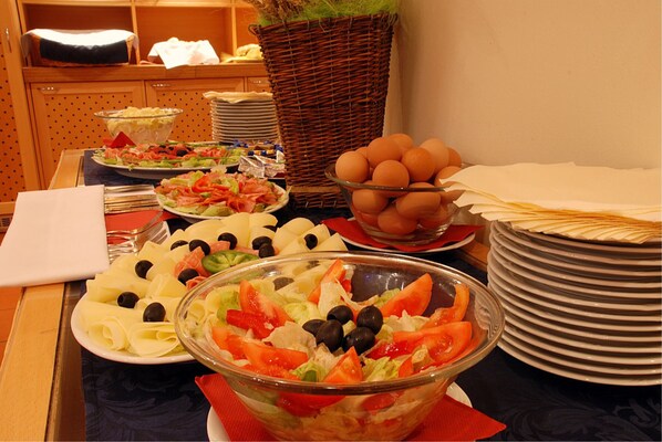 Uma mesa de buffet com diversos pratos, incluindo saladas, frutas e ovos.