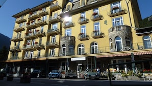 A yellow building with multiple balconies, a sign reading "Hotel Mozart," and a restaurant named "RESTAURANT" in the background. - Hotel Mozart Bad Gastein (Bad Gastein)