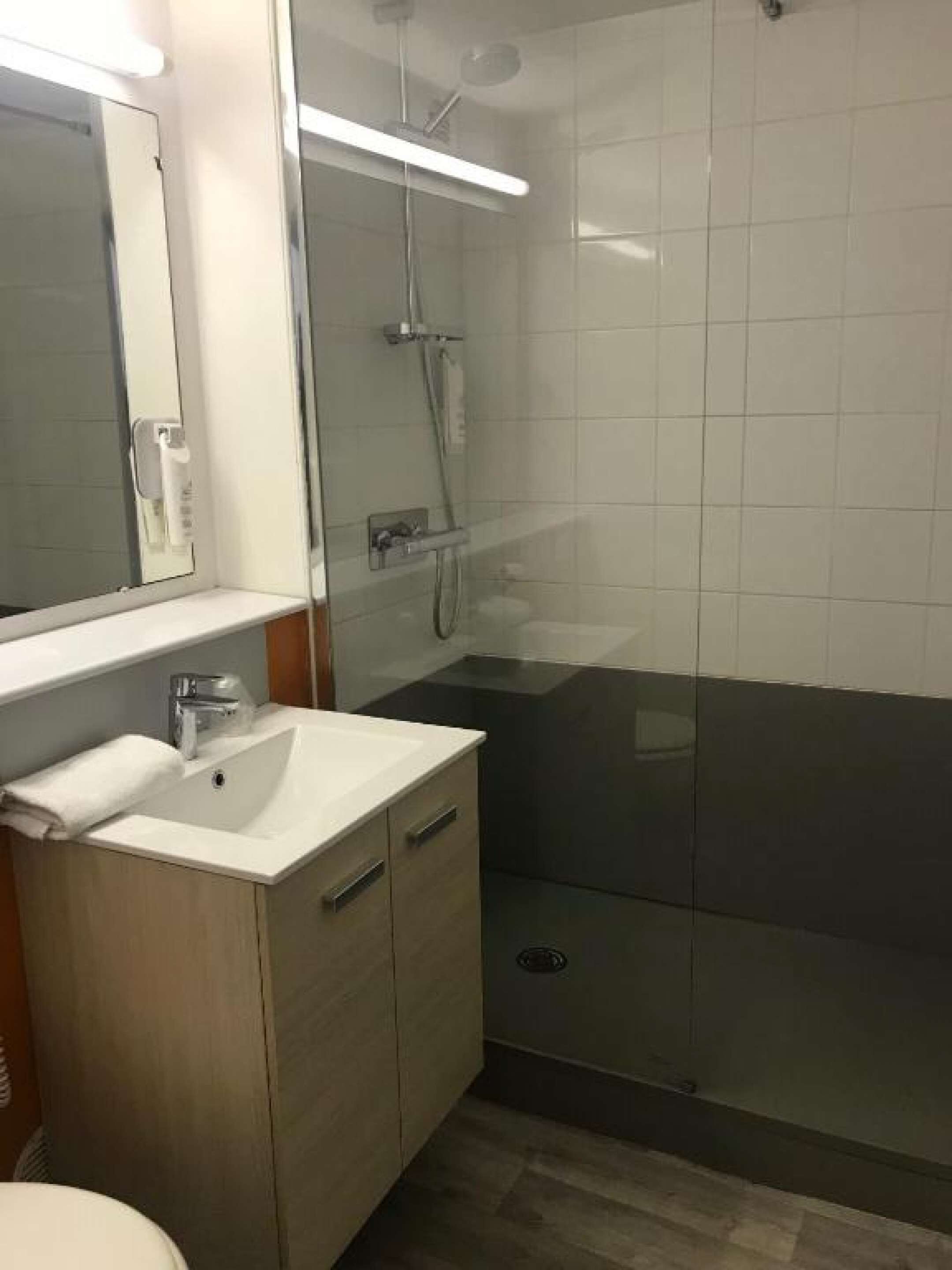 Un baño moderno con cabina de ducha de vidrio, un lavabo blanco y un espejo encima.