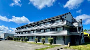 Un hôtel moderne à plusieurs étages, doté d’un parking et surplombant un ciel d’un bleu éclatant.