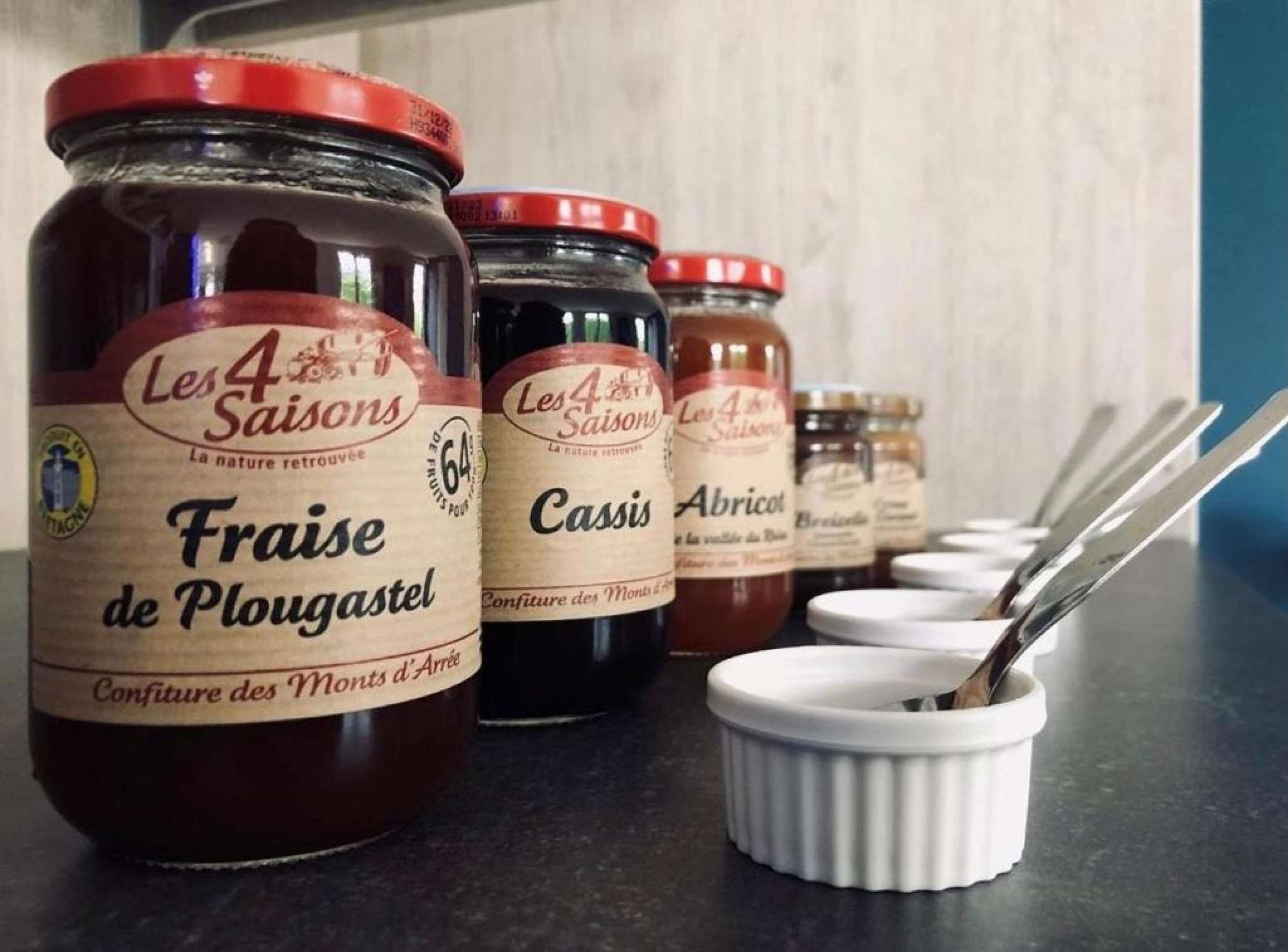 Plusieurs bocaux de fruits et de légumes conservés sont posés sur un plan de travail de cuisine.