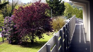 A pathway with a metal railing, surrounded by trees with purple leaves, and a view of a hilly landscape in the background. - Hotel Campanile Auxerre - Monéteau (Moneteau)