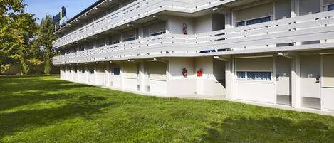 A multi-story hotel with a uniform exterior, balconies, and a well-maintained lawn.