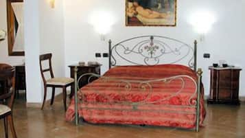 A bedroom with a metal bed frame, a red bedspread, a wooden chair, and a painting on the wall.