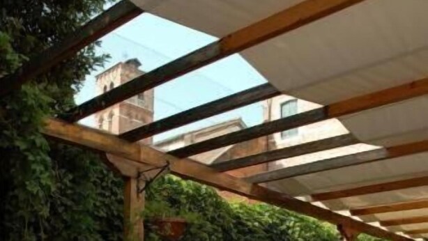 An outdoor dining area with a table set for breakfast, surrounded by greenery and a pergola. - Cà dei Leoni (Venice)