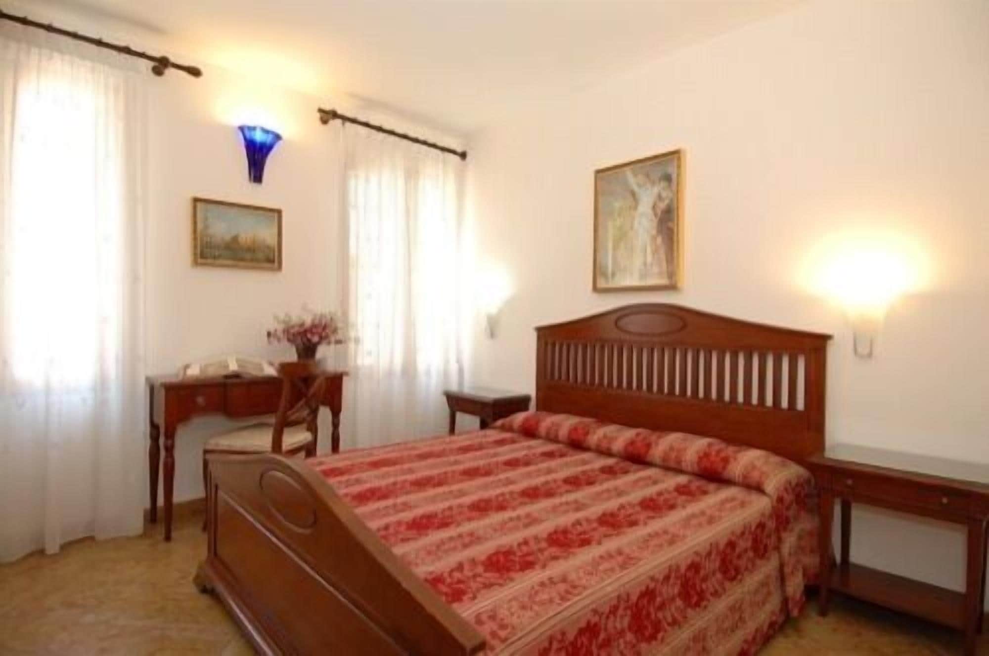 Une chambre à coucher avec un lit en bois, un bureau, une chaise et deux lampes fixées au mur.