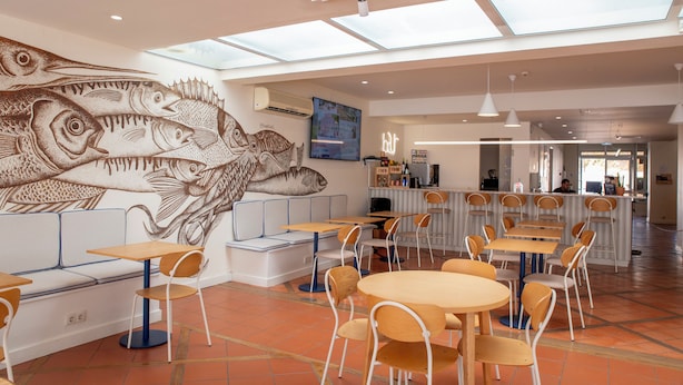 A restaurant with a mural of fish, tables, chairs, and a bar area. - WOT Lagos Montemar Soul (Lagos)