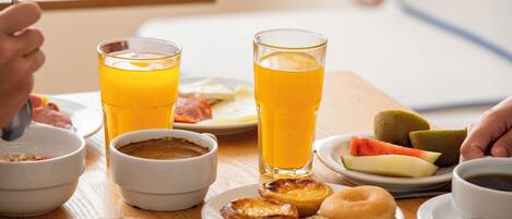 Une table de petit-déjeuner avec divers aliments et boissons, notamment du jus d’orange, des viennoiseries et un croissant.