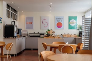 A modern kitchen with a central island, white cabinetry, and wooden chairs.