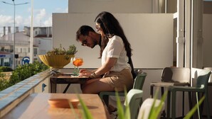A couple seated at an outdoor table with a potted plant and a drink. - WOT Lagos Montemar Soul (Lagos)