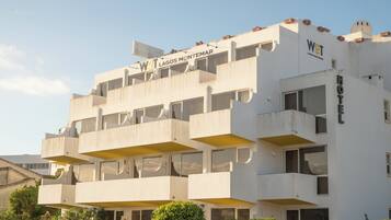 A multi-story hotel with balconies, a satellite dish, and a sign indicating it is a WOT hotel in Lagos Montemar.