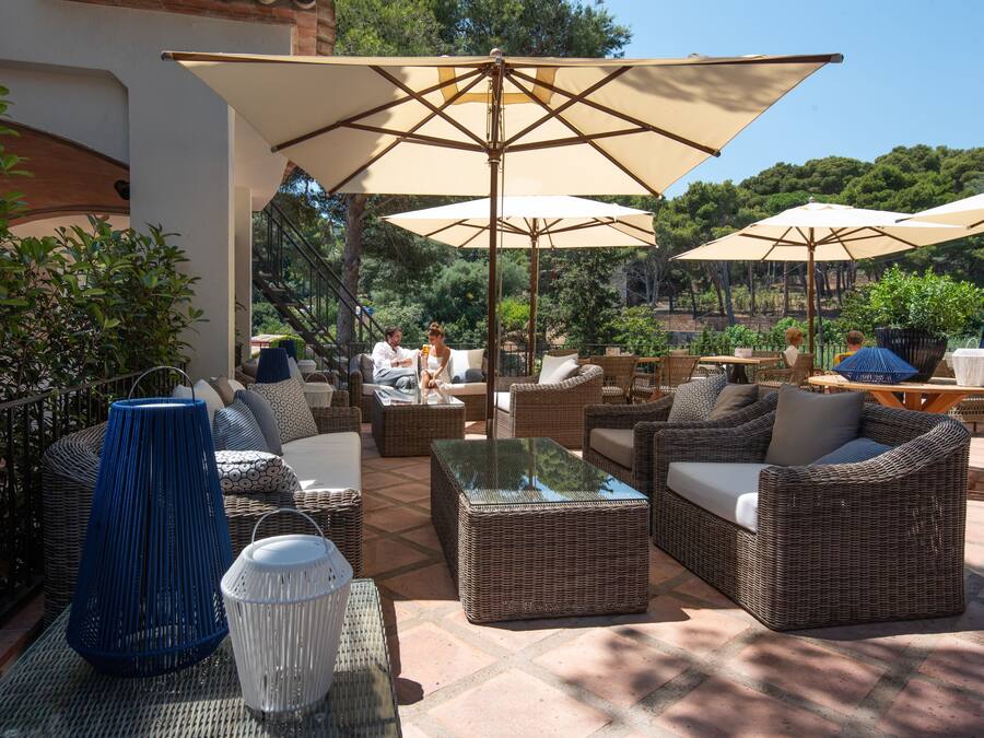 An outdoor patio with wicker furniture, large umbrellas, and potted plants.