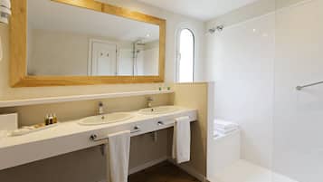 A modern bathroom with two sinks, a large mirror, and a shower area.