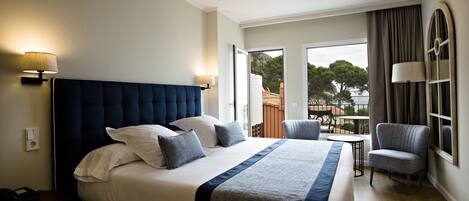 A large bed with a dark headboard, two bedside lamps, and a view of the outdoors through a door.